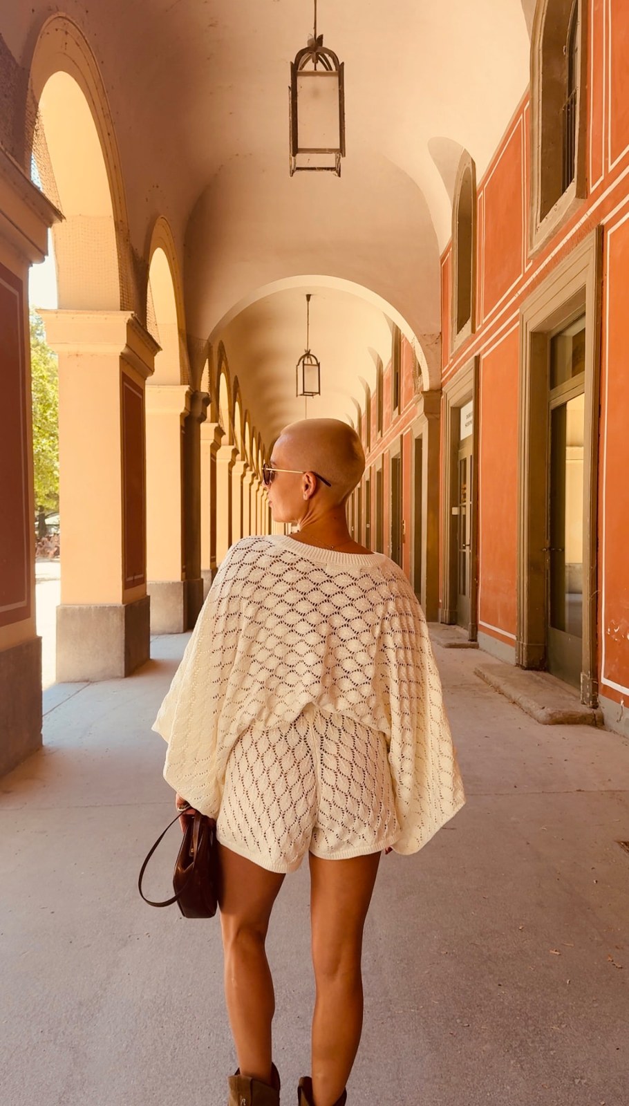 Kiva beneath sunlit arches in a crochet outfit