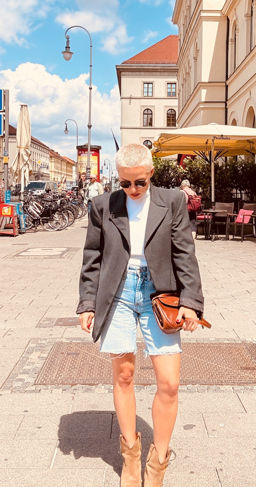 Kiva in sunglasses and a blazer on a sunny city street